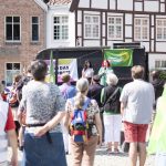 Auf der Bühne vor Demo-Teilnehmenden stehen Mai und Britta, die für Bündnis 90/Die Grünen und die Grüne Jugend einen Wortbeitrag geben